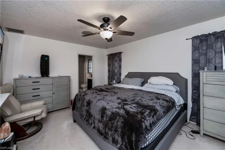 Bedroom featuring a textured ceiling, light carpet, and ceiling fan