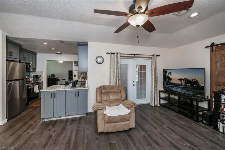 Living room featuring a barn door, ceiling fan, a textured ceiling, and dark hardwood / wood-style flooring