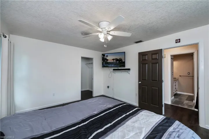 Unfurnished bedroom with ceiling fan, a textured ceiling, a closet, and dark hardwood / wood-style flooring