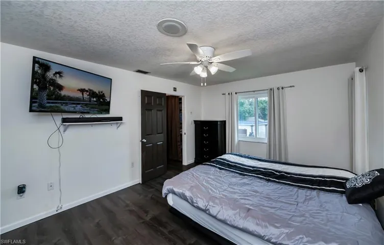 Bedroom with a textured ceiling, ceiling fan, and dark hardwood / wood-style floors