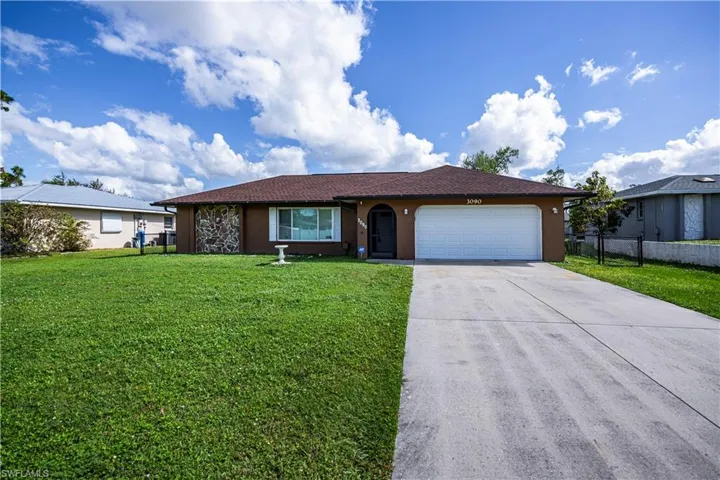 Ranch-style house featuring a garage and a front lawn