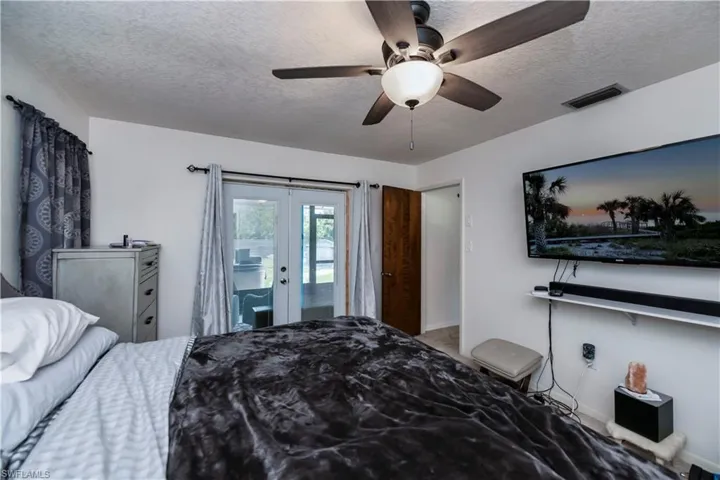 Bedroom featuring access to outside, french doors, ceiling fan, and a textured ceiling