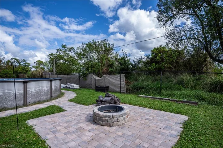 View of patio with an outdoor fire pit and a fenced in pool