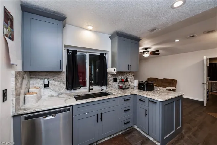 Kitchen featuring backsplash, dark hardwood / wood-style flooring, sink, dishwasher, and ceiling fan