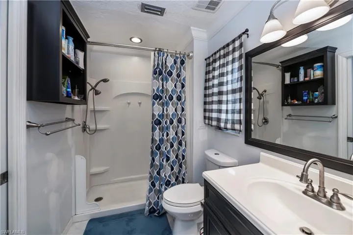 Bathroom featuring walk in shower, ornamental molding, a textured ceiling, vanity, and toilet