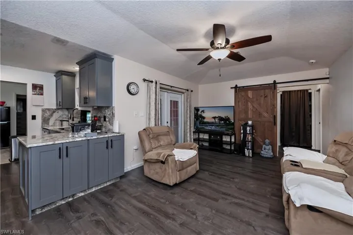 Kitchen featuring light stone countertops, ceiling fan, dark hardwood / wood-style flooring, and gray cabinets Along with the livingroom