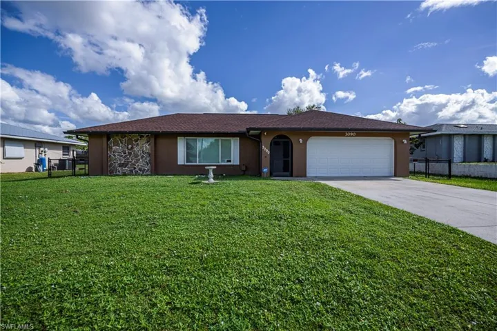 Ranch-style house featuring a front lawn and a garage