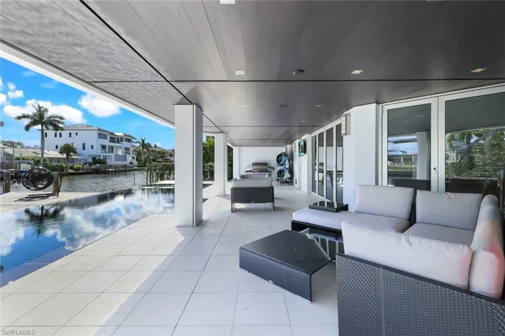 View of patio with an outdoor living space, a water view, and a dock