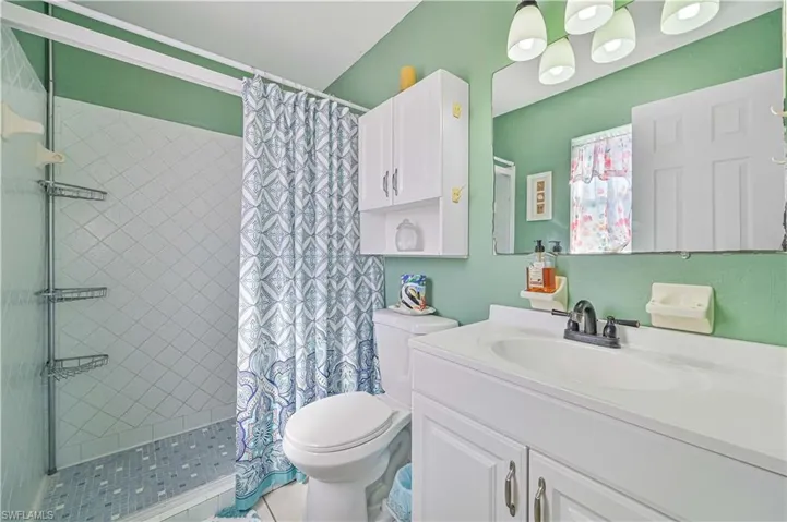 Bathroom with vanity, curtained shower, and toilet