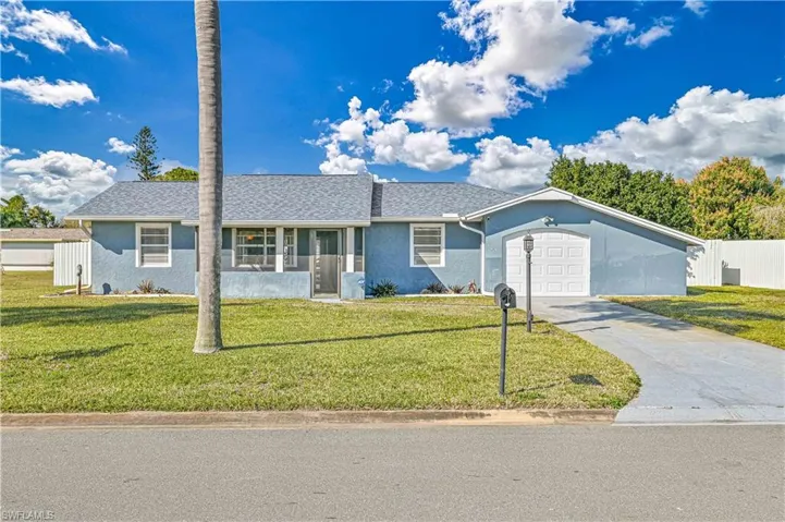 Single story home with a garage and a front lawn