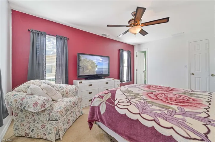 Carpeted bedroom featuring ceiling fan and multiple windows