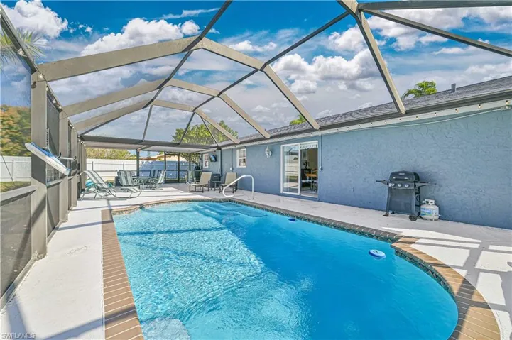 View of pool with area for grilling, a patio, and glass enclosure