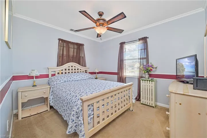 Bedroom featuring radiator heating unit, ornamental molding, light colored carpet, and ceiling fan