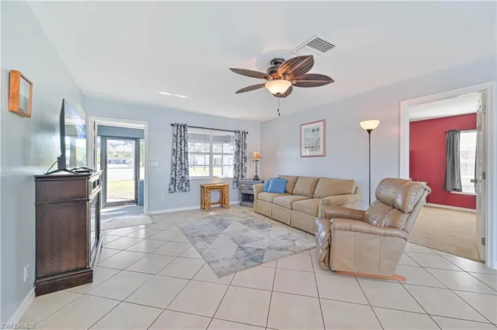 Living room featuring light tile patterned floors and ceiling fan