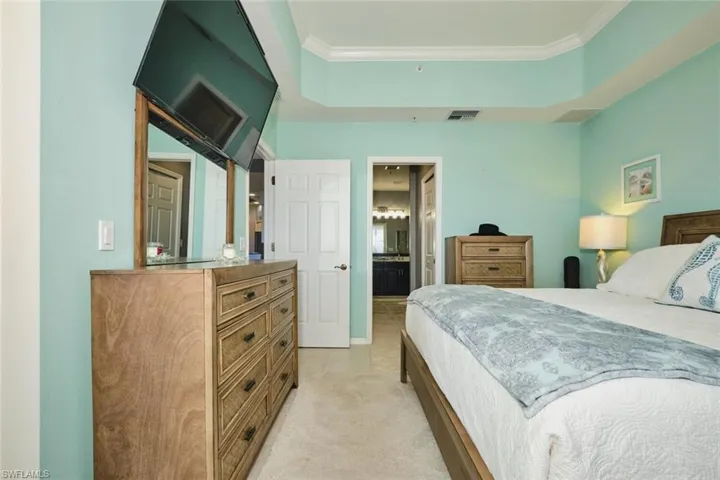 Bedroom with crown molding, connected bathroom, and light colored carpet