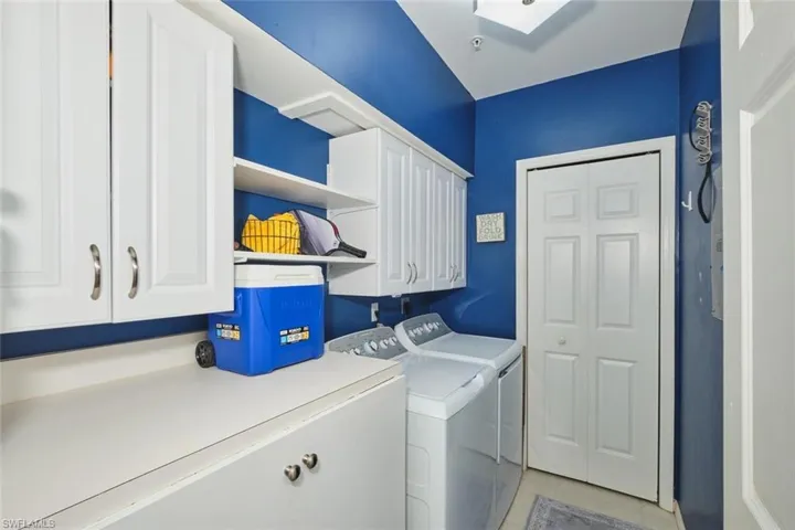Laundry area featuring cabinet space, separate washer and dryer, and light tile patterned flooring
