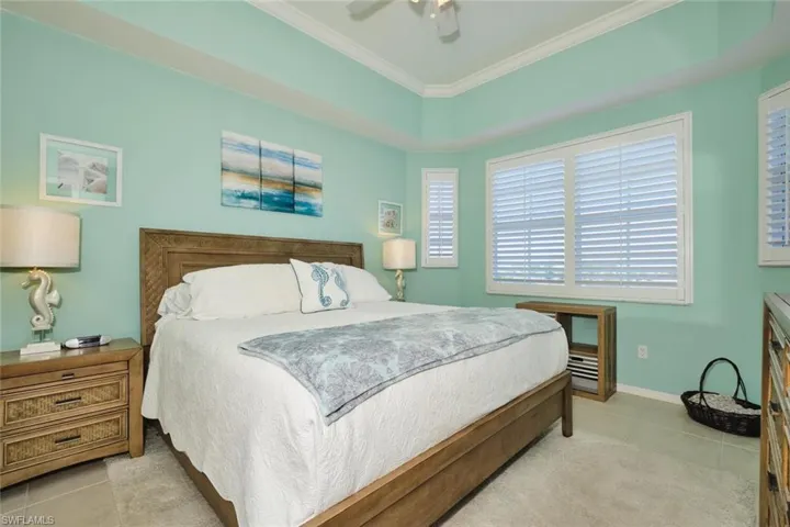 Bedroom featuring a ceiling fan, light tile patterned floors, and crown molding