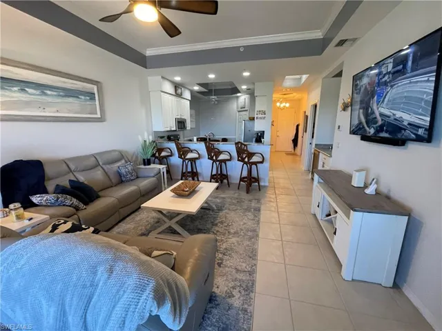 Living area featuring light tile patterned floors, ceiling fan, ornamental molding, and recessed lighting
