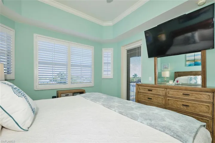 Bedroom with multiple windows, ornamental molding, and access to outside