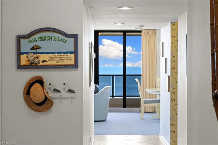 Entry hall featuring a wall of windows, light tile & water view
