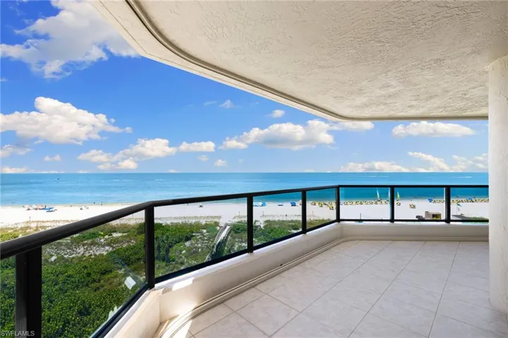 Wrap around balcony featuring view of water and beach