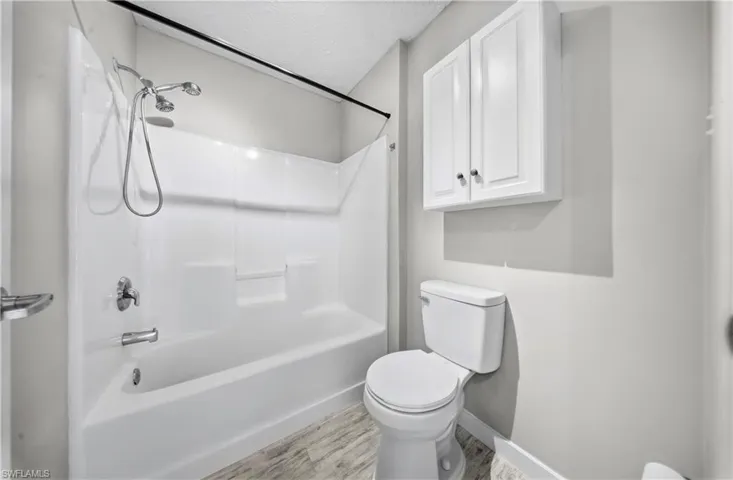 Full bathroom featuring a textured ceiling, bathtub / shower combination, and light wood-style floors