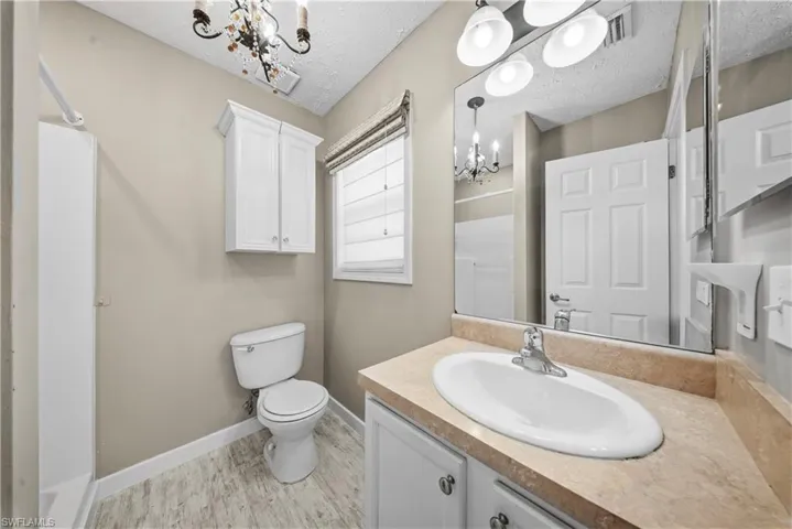 Bathroom featuring hanging lights, vanity, and a textured ceiling