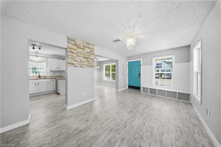 Unfurnished living room with suspended lighting, a textured ceiling, and light wood-style floors