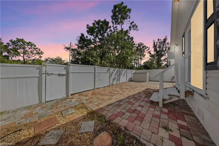 Patio terrace at dusk featuring a patio area, a gate, and a fenced backyard