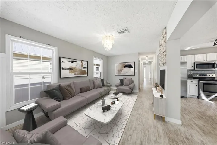 Living area with a textured ceiling, light wood finished floors, and suspended lighting