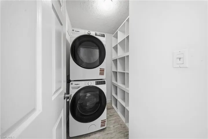 Laundry room featuring a textured ceiling and stacked washer / drying machine