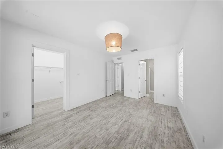 Unfurnished bedroom featuring a walk in closet and light wood-style floors