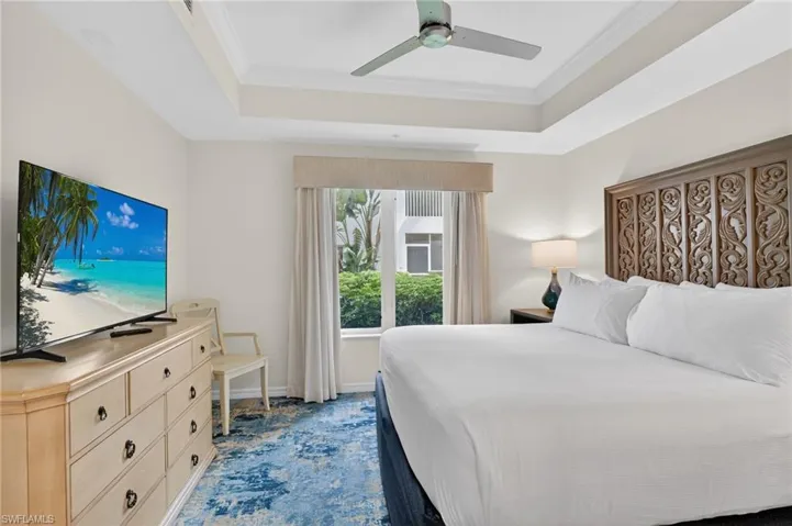 Bedroom with crown molding, a ceiling fan, a tray ceiling, and carpet flooring