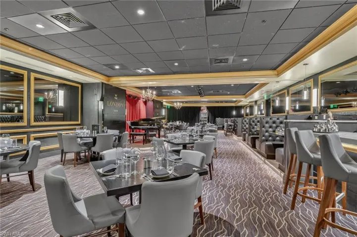 Dining area with dark colored carpet, a raised ceiling, and a paneled ceiling