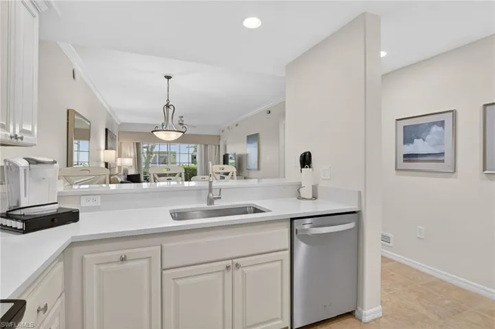Kitchen featuring dishwasher, white cabinets, decorative light fixtures, light stone countertops, and crown molding
