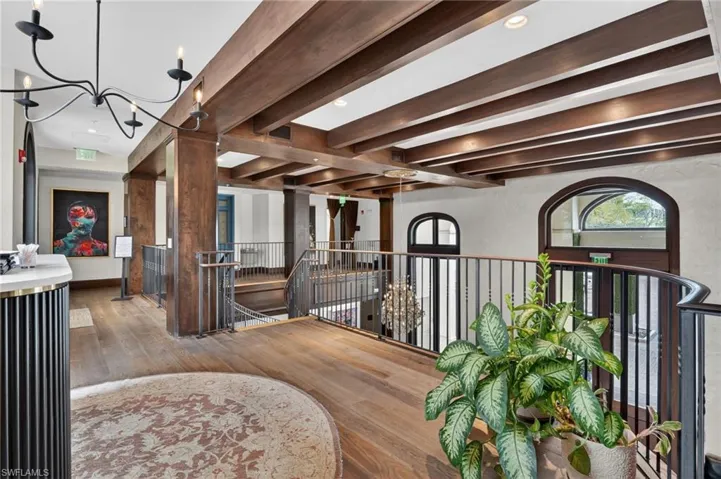 Corridor with beamed ceiling, an upstairs landing, hardwood / wood-style flooring, and hanging lights