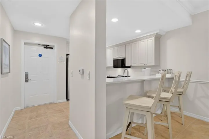 Kitchen featuring a kitchen bar, light tile patterned floors, recessed lighting, and a peninsula