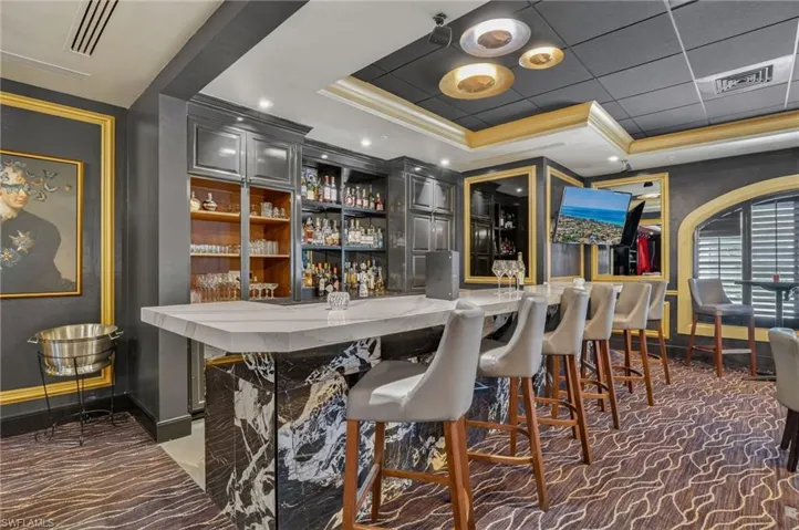 Bar with gray cabinets, ornamental molding, and recessed lighting