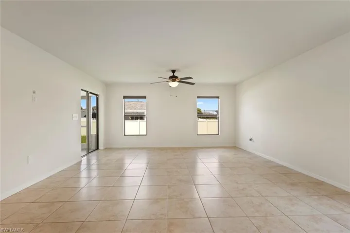 Empty room with light tile patterned floors and ceiling fan