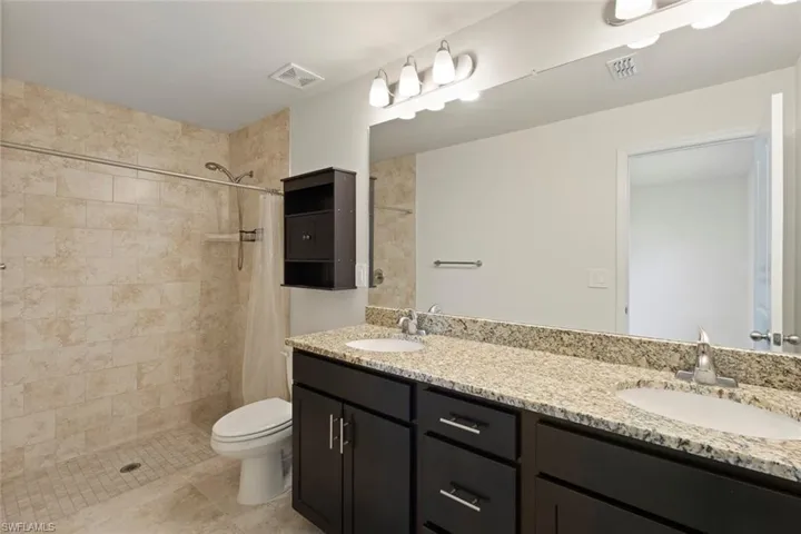 Bathroom featuring a stall shower, double vanity, and light tile patterned flooring