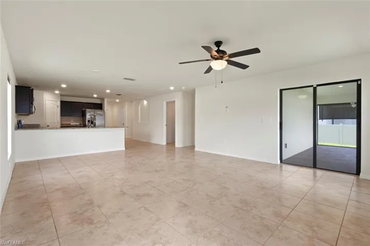 Unfurnished living room with recessed lighting, light tile patterned flooring, a ceiling fan, and arched walkways