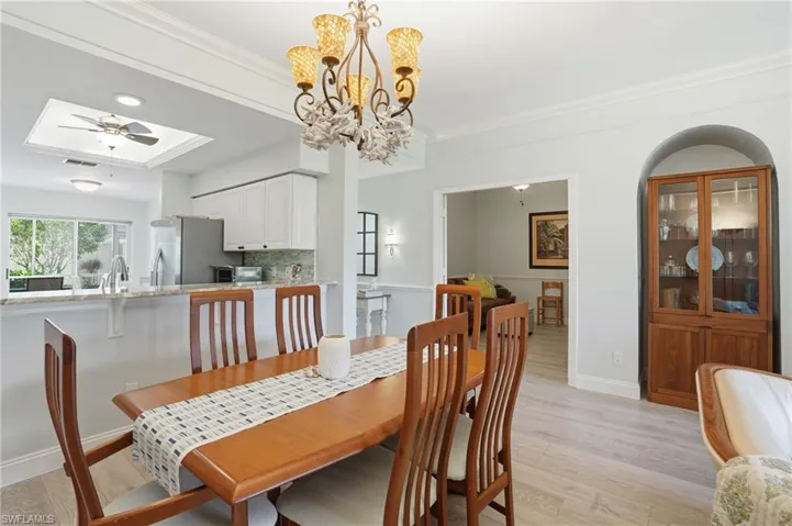 Dining area with LVP flooring and a tray ceiling, ornamental molding, and a chandelier