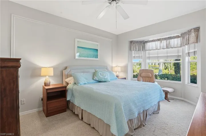 Carpeted bedroom with ceiling fan, king bed and bay window view