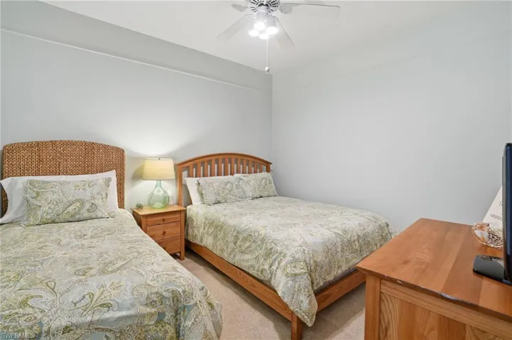 Bedroom featuring light colored carpet, ceiling fan and 2 twin beds.