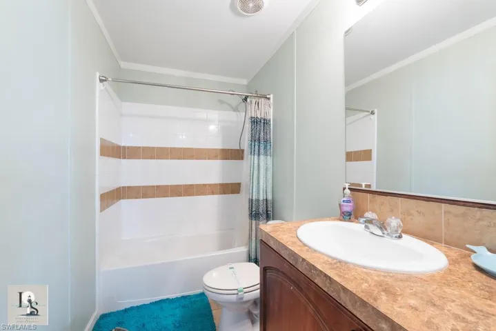 Bathroom with shower / tub combo, vanity, ornamental molding, and decorative backsplash