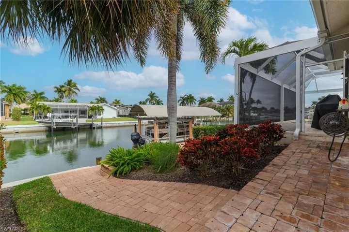 View of patio with a lanai, boat lift, a boat dock, and a water view