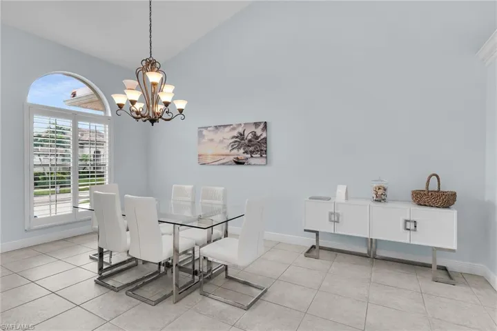 Dining room featuring vaulted ceiling, light tile patterned flooring, and a chandelier