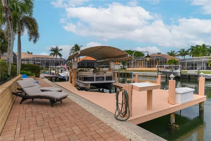 Dock area with boat lift, a water view, and a residential view