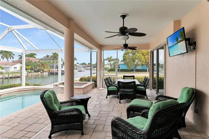 View of patio with a sunroom, a lanai, a ceiling fan, and outdoor dining area