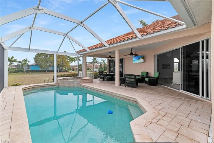 View of swimming pool with a patio area, a sunroom, glass enclosure, a pool with connected hot tub, and outdoor dining space